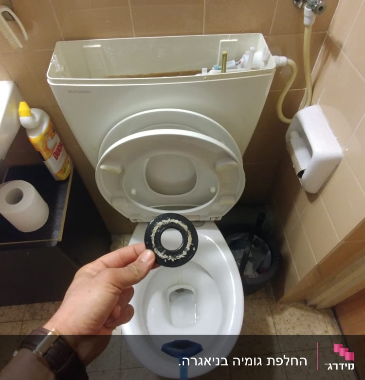 יד מחזיקה אטם גומי מול אסלה פתוחה